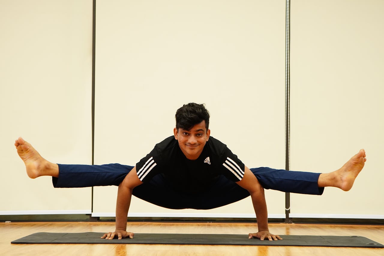 Adult man practicing an advanced yoga pose on a mat indoors, showcasing balance and strength.